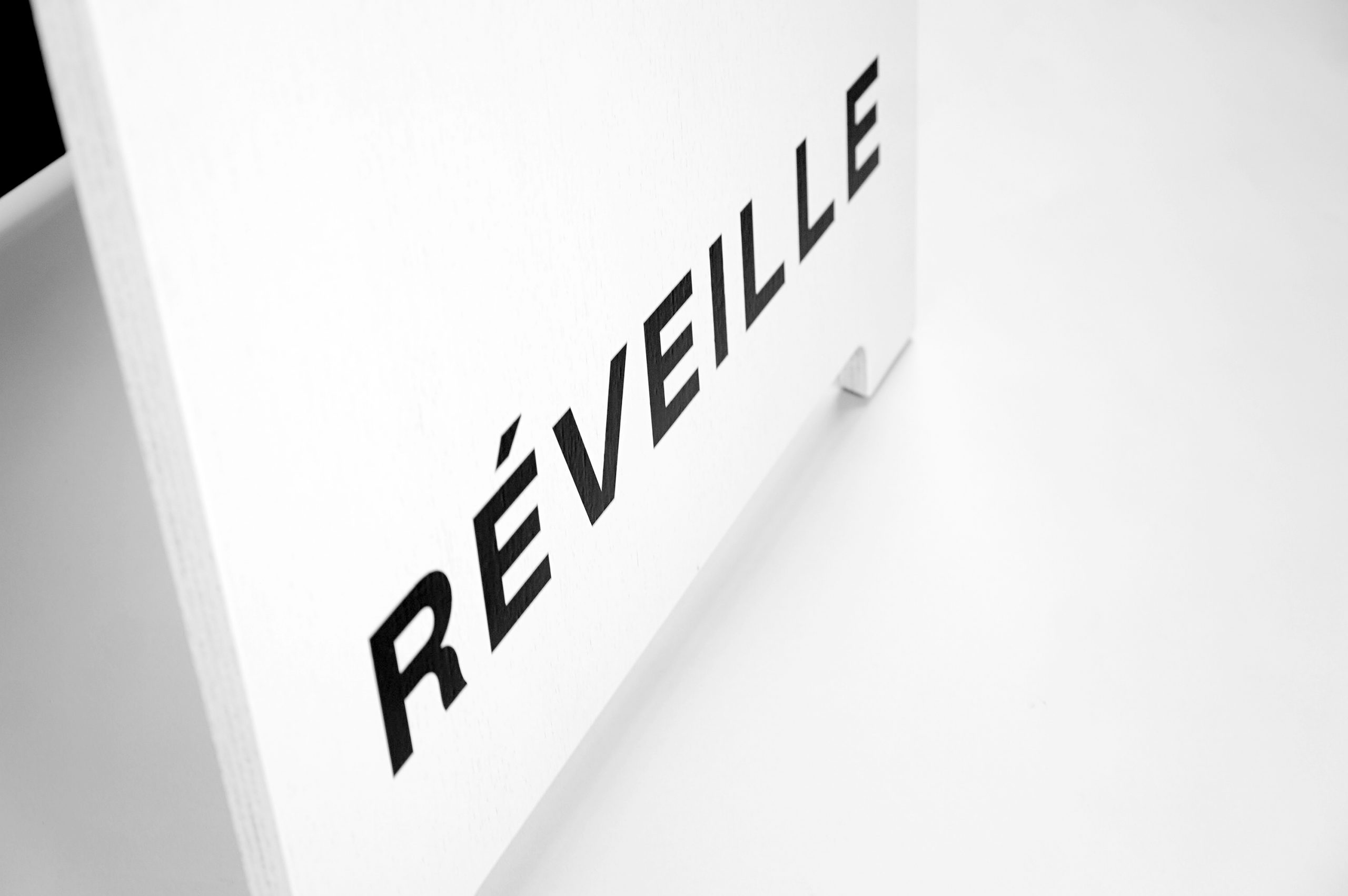 Black and white painted A-frame sign with alternating colors for Cafe Réveille, a San Francisco based specialty coffee roaster and coffee shop chain.