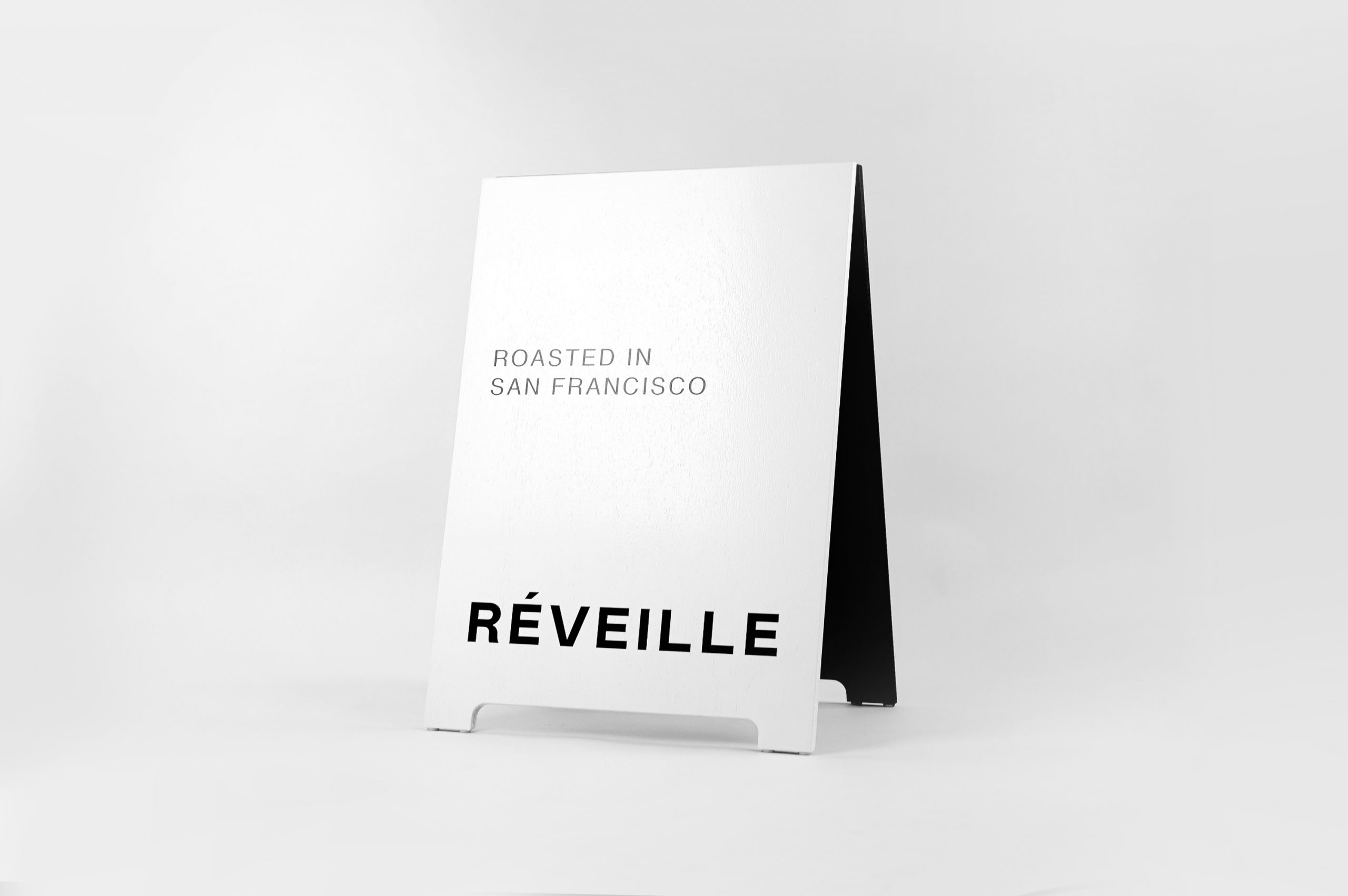 Black and white painted A-frame sign with alternating colors for Cafe Réveille, a San Francisco based specialty coffee roaster and coffee shop chain.