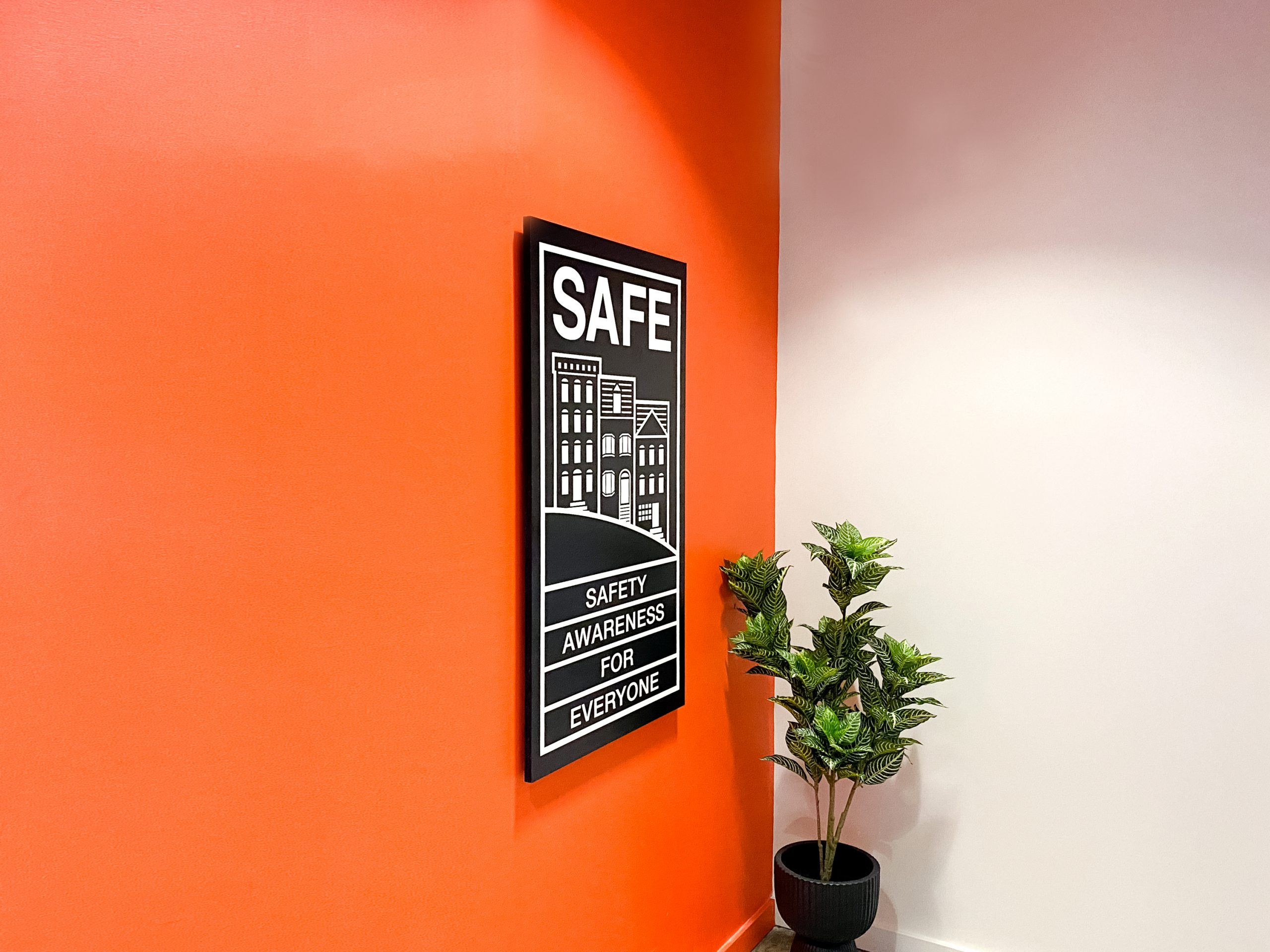 Illuminated, black-and-white, poster-style lightbox sign for the elevator vestibule of SAFE, an organization that partners with the San Francisco Police Department to educate and empower San Franciscans to build safer neighborhoods.