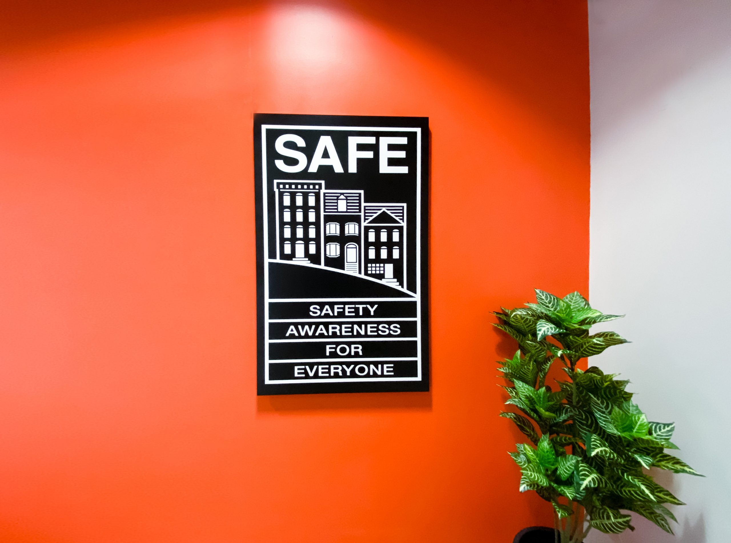 Illuminated, black-and-white, poster-style lightbox sign for the elevator vestibule of SAFE, an organization that partners with the San Francisco Police Department to educate and empower San Franciscans to build safer neighborhoods.