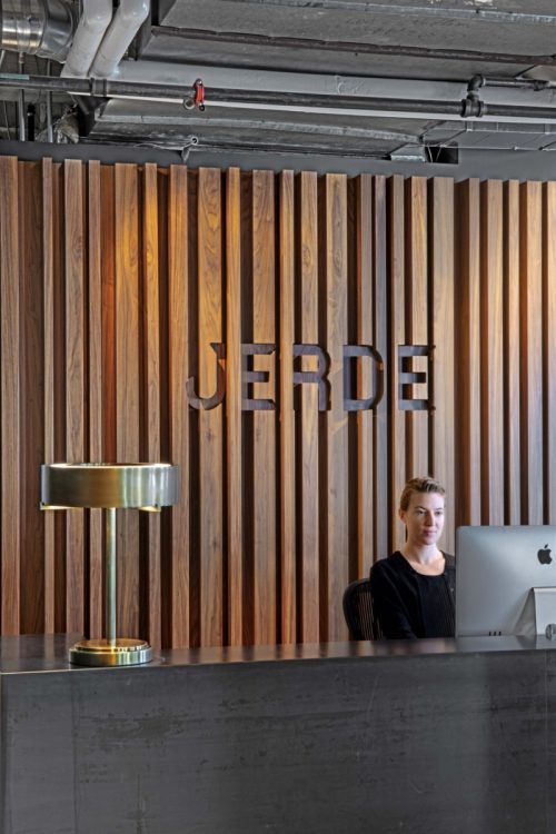 Logo cut into custom dark wood slat wall behind reception desk at the Los Angeles office of Jerde, an architecture and design form. (Photo: Eric Laignel)