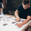 Lush hanging retail blade sign in black stained wood with raised dimensional white letters - process