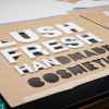 Lush hanging retail blade sign in black stained wood with raised dimensional white letters - process