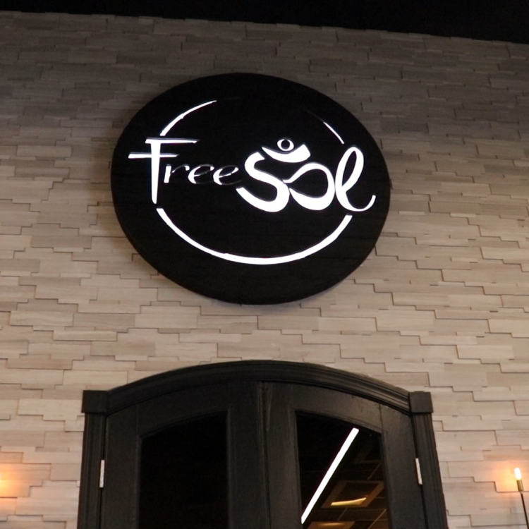 Torched wood, interior-lit, large circular wall sign for FreeSol, a fitness studio located in Styles Studios, a boutique fitness studio in Peoria, IL.