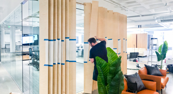 Optical-illusion, multi panel wood sign / privacy screen at the San Francisco office of Compass, a modern real estate platform.