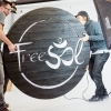 Torched wood, interior-lit, large circular wall sign for FreeSol, a fitness studio located in Styles Studios, a boutique fitness studio in Peoria, IL.