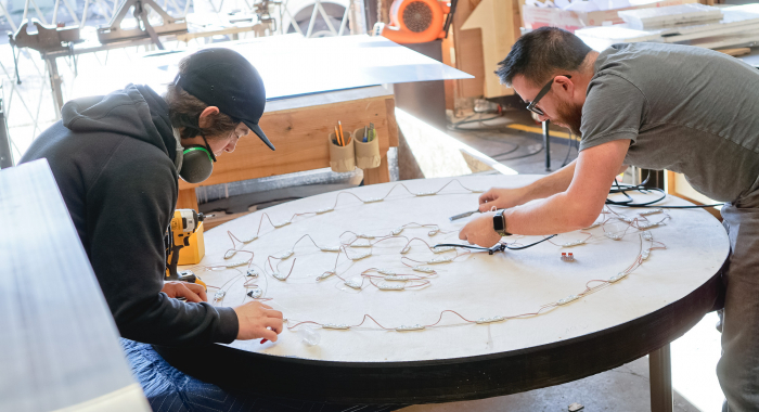 Torched wood, interior-lit, large circular wall sign for FreeSol, a fitness studio located in Styles Studios, a boutique fitness studio in Peoria, IL.