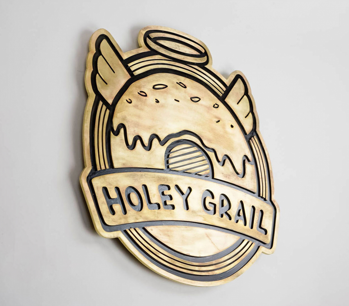 Patinated, retro brass sign for Holey Grail, a donut shop based in Hawaii.