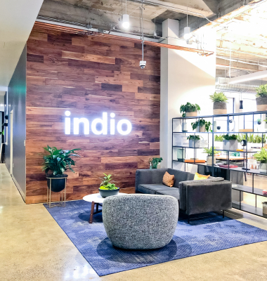 Full wall installation with dark wood and an illuminated, built-in logo for the San Francisco lobby of Indio, a company that simplifies the insurance application process for brokers and their clients.