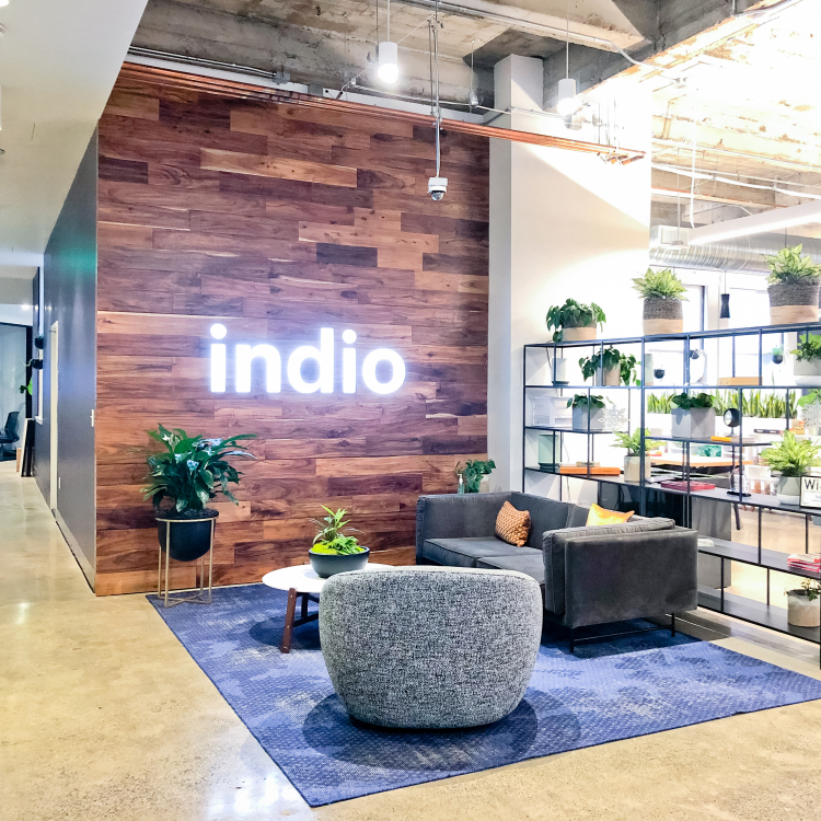 Full wall installation with dark wood and an illuminated, built-in logo for the San Francisco lobby of Indio, a company that simplifies the insurance application process for brokers and their clients.