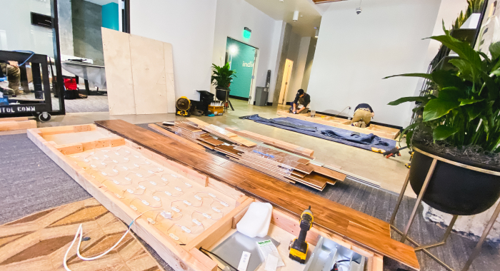 Full wall installation with dark wood and an illuminated, built-in logo for the San Francisco lobby of Indio, a company that simplifies the insurance application process for brokers and their clients.