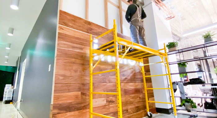 Full wall installation with dark wood and an illuminated, built-in logo for the San Francisco lobby of Indio, a company that simplifies the insurance application process for brokers and their clients.