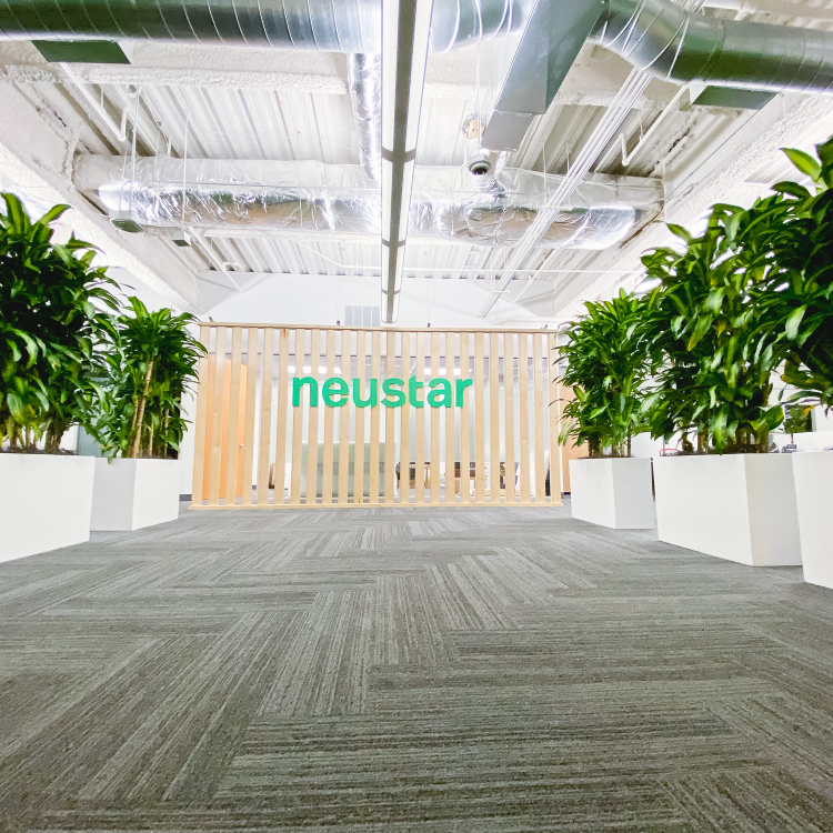 Wood slat dividing wall wiht green logo for lobby/reception desk area at the San Francisco office of Neustar, an American technology company that provides real-time information and analytics.