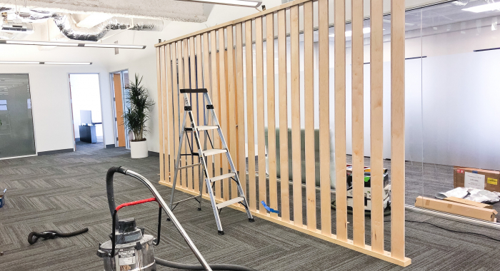 Wood slat dividing wall wiht green logo for lobby/reception desk area at the San Francisco office of Neustar, an American technology company that provides real-time information and analytics.