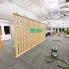 Wood slat dividing wall wiht green logo for lobby/reception desk area at the San Francisco office of Neustar, an American technology company that provides real-time information and analytics.