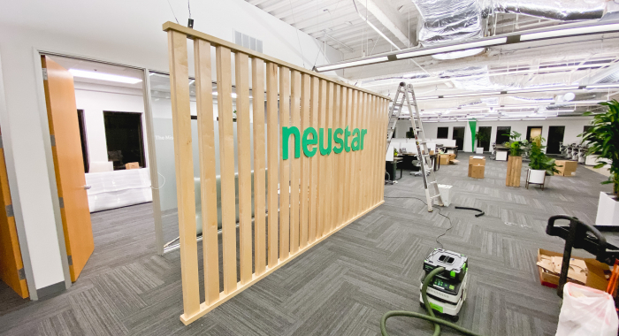 Wood slat dividing wall wiht green logo for lobby/reception desk area at the San Francisco office of Neustar, an American technology company that provides real-time information and analytics.