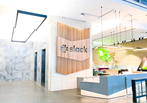 Modern, large-scale slat wood lobby sign on concrete wall at the San Francisco lobby of Slack, an American cloud-based set of team collaboration tools and services.