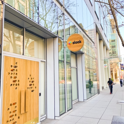 Wood blade sign with dimensional color logo and brass hardware for the San Francisco brand space at Slack, an American cloud-based set of team collaboration tools and services.