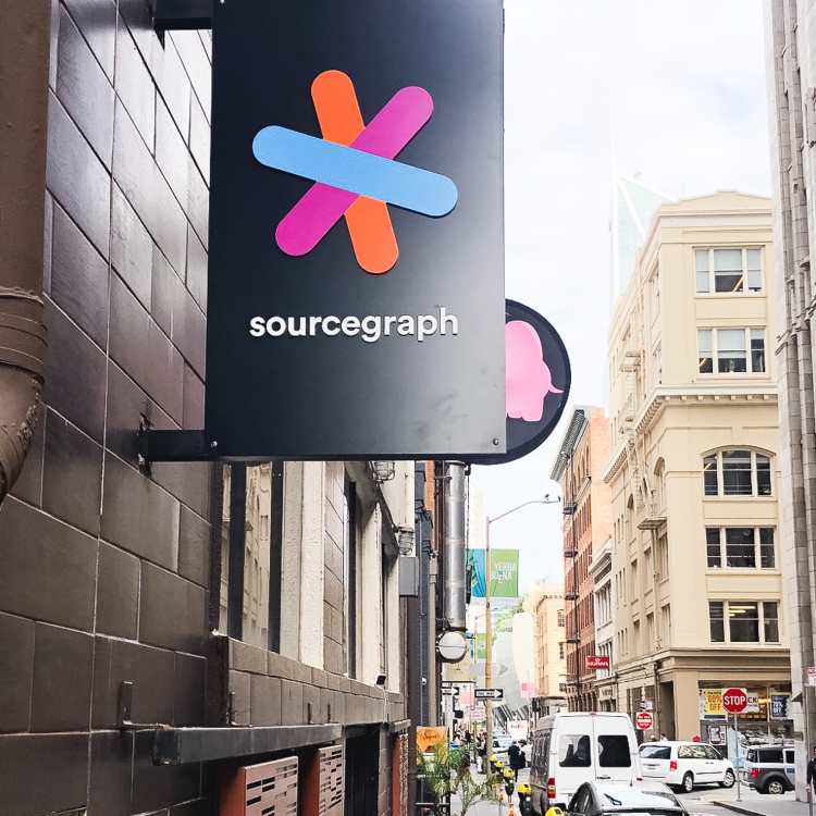 Simple black blade sign with colored logo for Sourcegraph, a San Francisco-based company that adds code intelligence to GitHub and other code hosts.