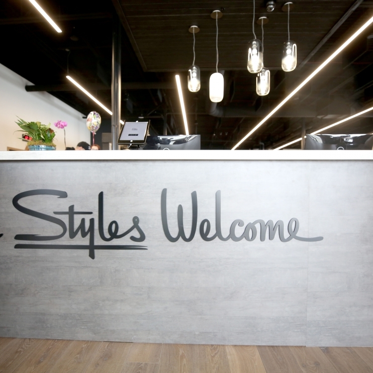 Black script front desk sign for the lobby at Styles Studios, a fitness club in Peoria, IL.